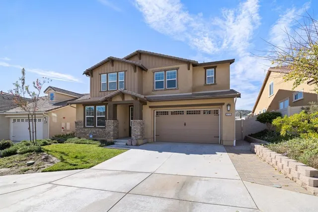 a view of a white house next to a yard with potted plants