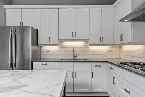 a kitchen with granite countertop white cabinets and stainless steel appliances