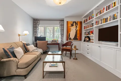 a living room with furniture a flat screen tv and a floor to ceiling window