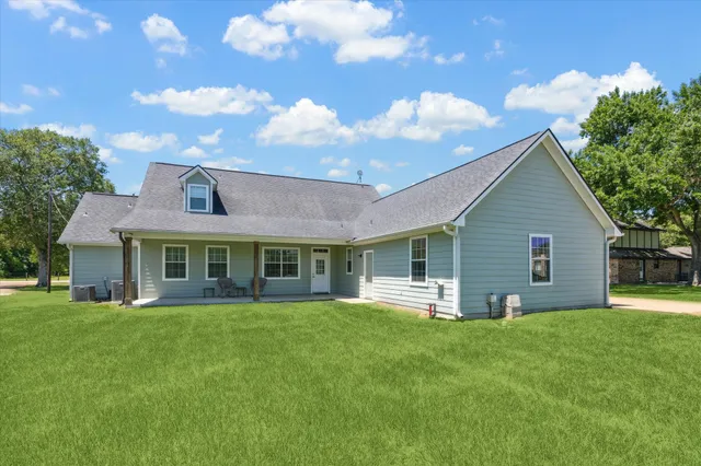a view of a house next to a big yard and large trees