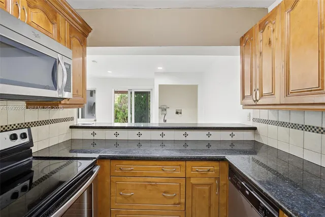 a kitchen with stainless steel appliances granite countertop a sink stove and microwave