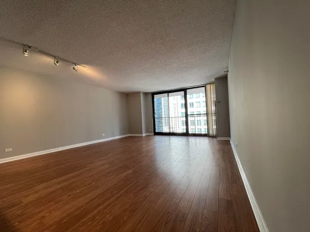 a view of an empty room with wooden floor and fan