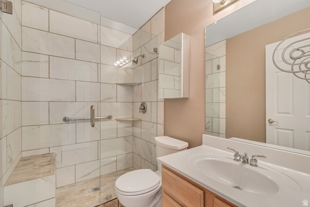 546 Wheatridge Road Tooele, UT 84074 - Photo 16 of 49 Spacious bathroom featuring a glass-enclosed shower with white tiled walls, an integrated shower bench, and a built-in shelf