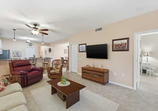 a living room with furniture a flat screen tv and kitchen view