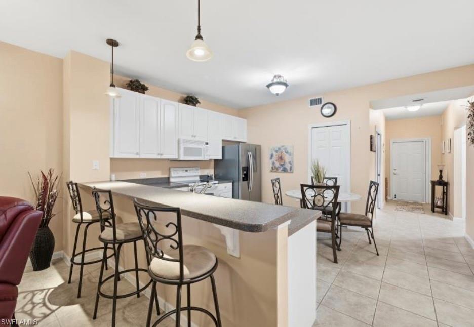 10024 Heather Lane, Unit 1001 Naples, FL 34119 - Photo 9 of 23 a kitchen with stainless steel appliances a table and chairs in it