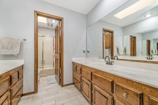 a spacious bathroom with a granite countertop sink a mirror and a shower