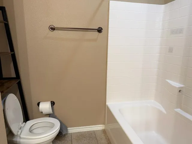 a white toilet sitting next to a bath tub