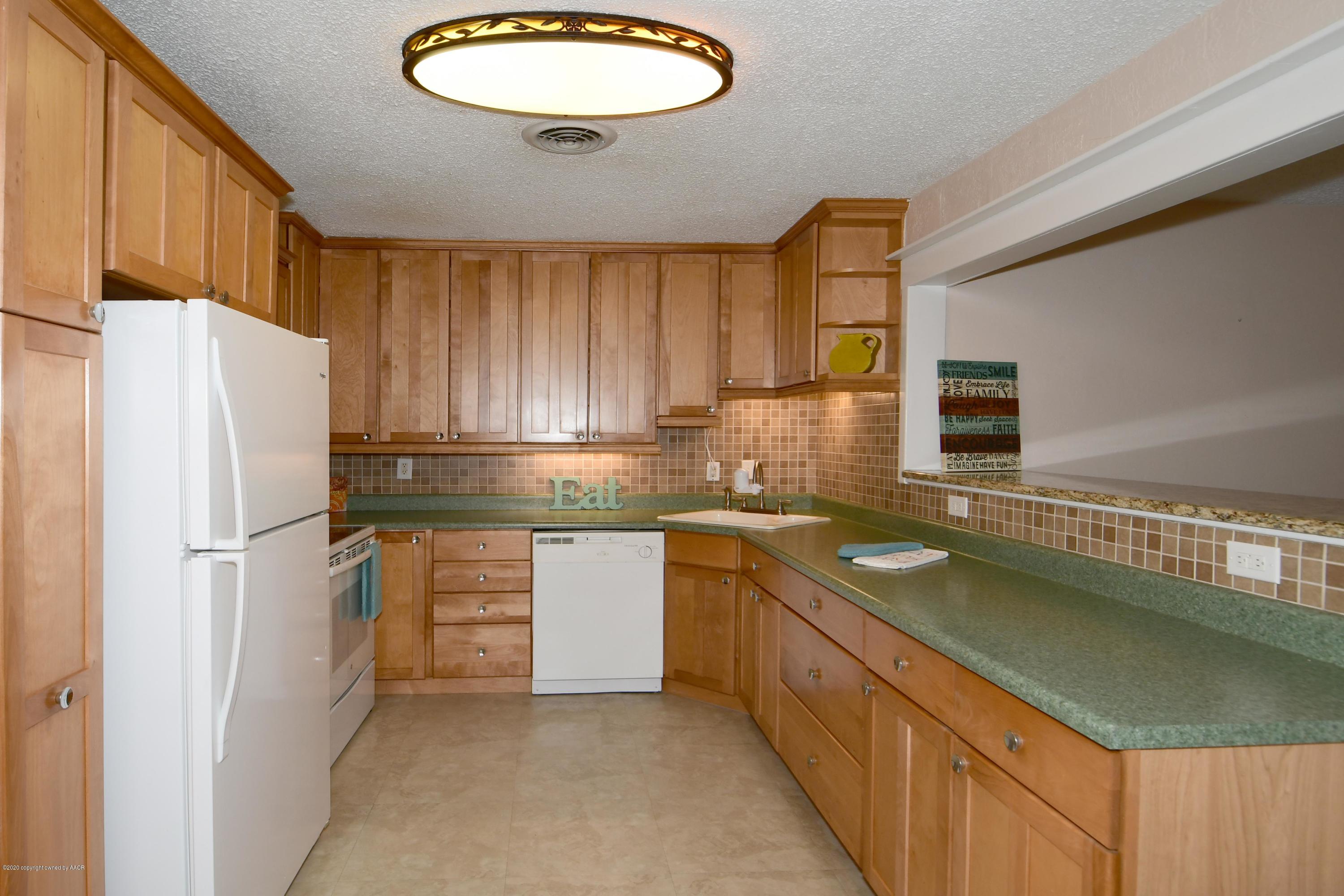 5204 South Travis Street Amarillo, TX 79110 - Photo 7 of 25 a kitchen with stainless steel appliances granite countertop a refrigerator a sink dishwasher a oven with white cabinets and wooden floor