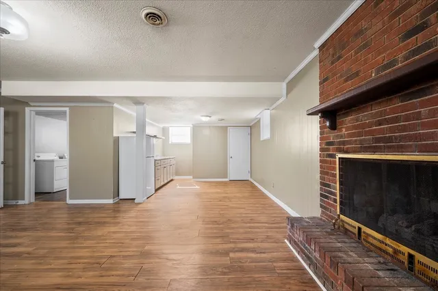 a view of empty room with wooden floor and fireplace