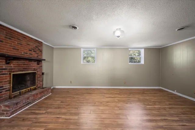 a view of an empty room with wooden floor and a fireplace