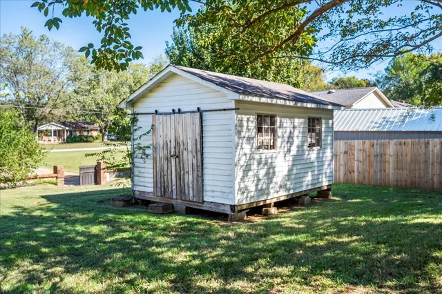 a view of a house with a yard and a large tree