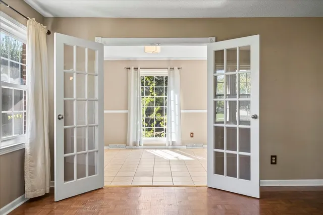 a view of an empty room with wooden floor and windows