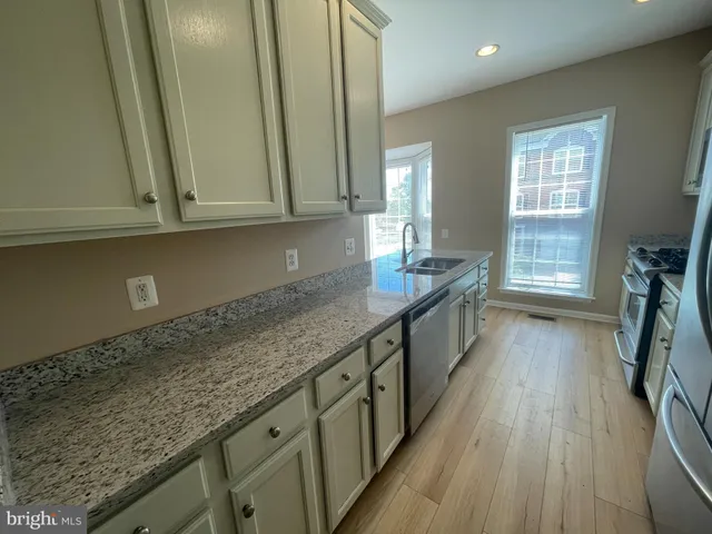 a kitchen with granite countertop a sink a stove and cabinets