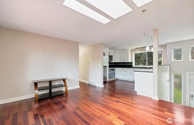 a view of empty room with wooden floor and kitchen