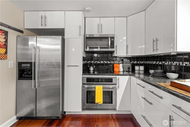 a kitchen with stainless steel appliances granite countertop a refrigerator a stove and a sink with wooden floor