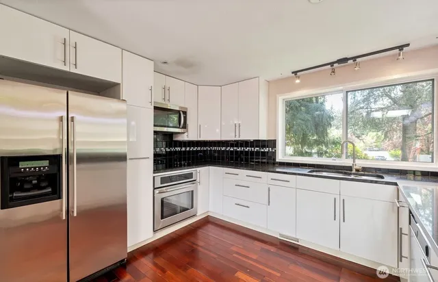 a kitchen with granite countertop stainless steel appliances a sink and cabinets
