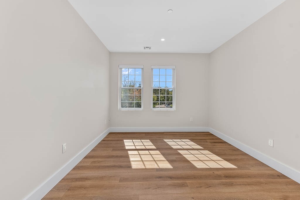 22 Everett Street, Unit 424 Westwood, MA 02090 - Photo 13 of 30 an empty room with wooden floor a exposed radiator and a window