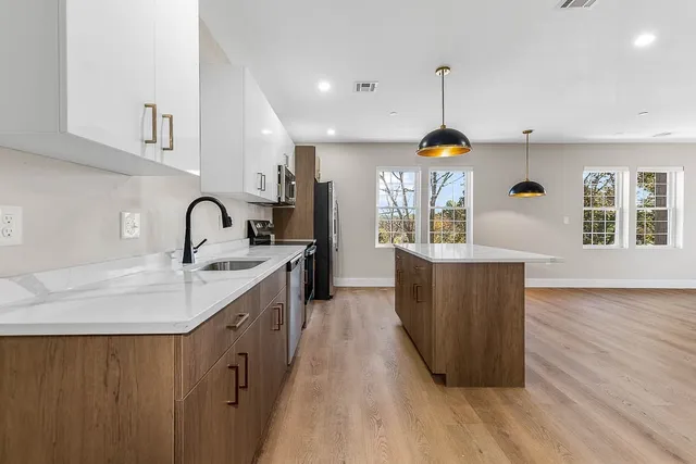 a kitchen with stainless steel appliances granite countertop a sink a stove and a wooden floors