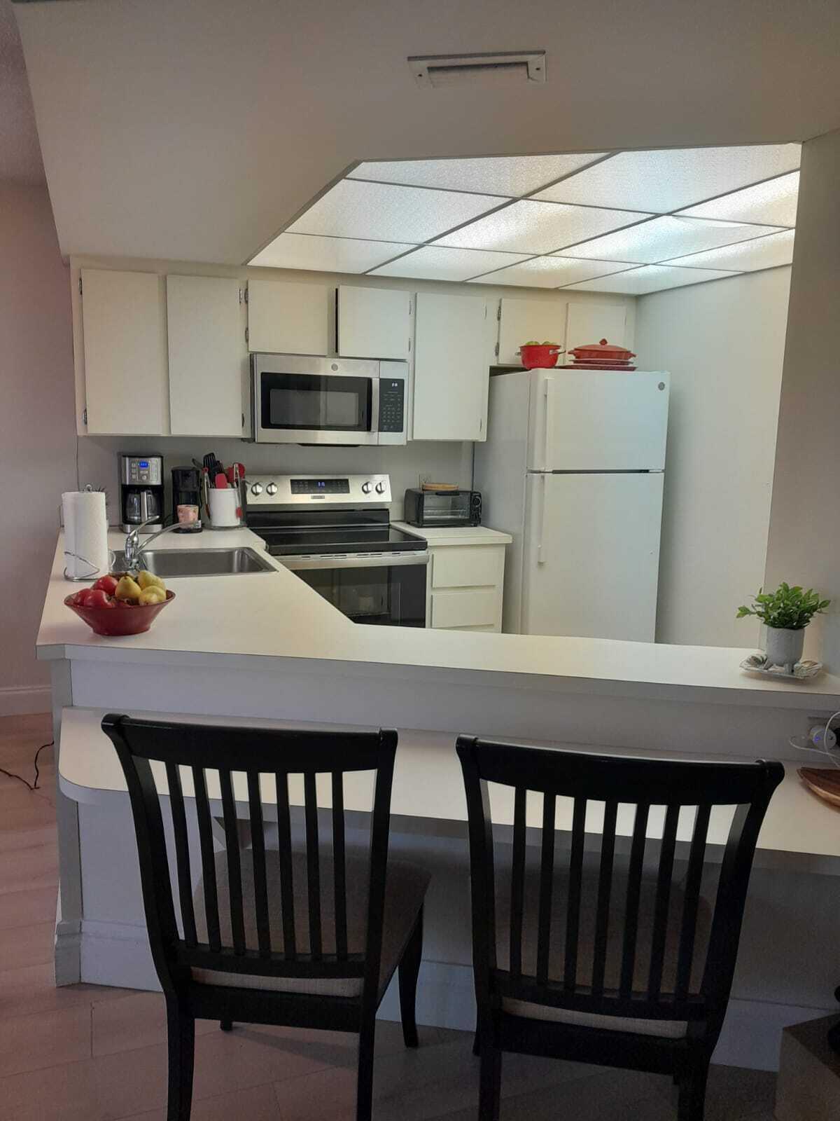 1605 Highway 1, Unit C302 Jupiter, FL 33477 - Photo 13 of 30 a kitchen with a dining table chairs refrigerator and microwave