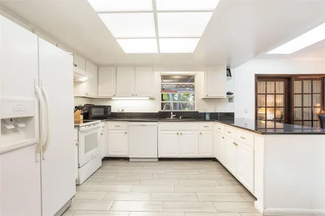 a kitchen with granite countertop white cabinets white stainless steel appliances with a sink and dishwasher