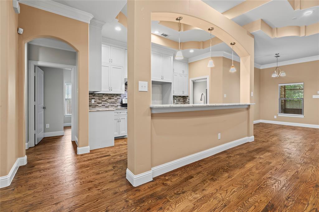 7806 Garner Road Rowlett, TX 75088 - Photo 8 of 34 an empty room with wooden floor and a kitchen