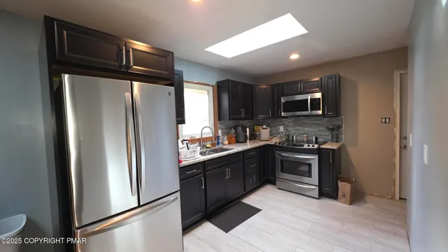a kitchen with granite countertop a refrigerator stove and sink