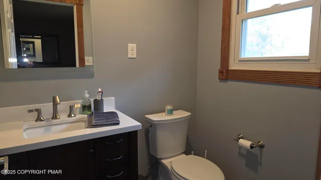 a bathroom with a toilet sink a mirror and window