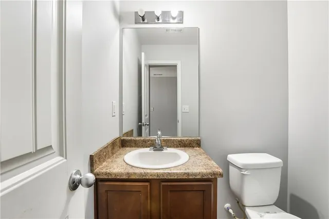 a bathroom with a granite countertop sink a toilet and a mirror
