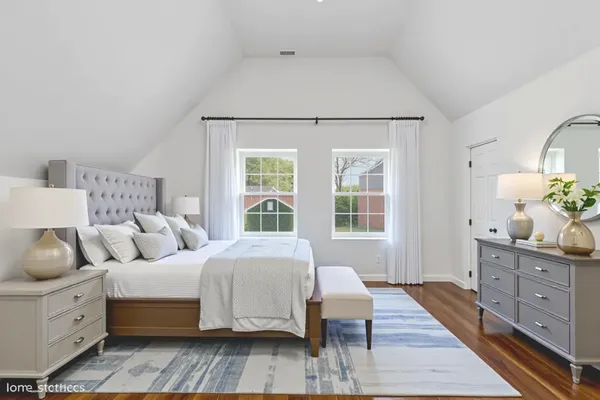 a spacious bedroom with a bed and wooden floor