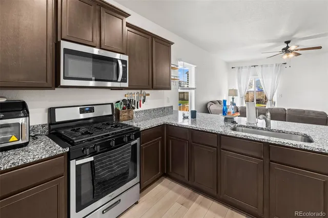 a kitchen with granite countertop a sink dishwasher stove and microwave with wooden cabinets