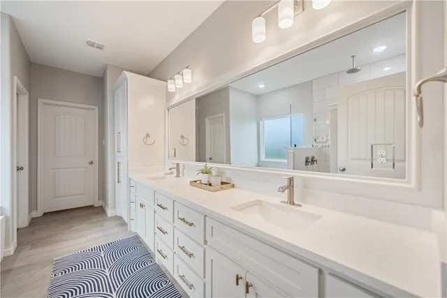 a spacious bathroom with double vanity a mirror and a shower