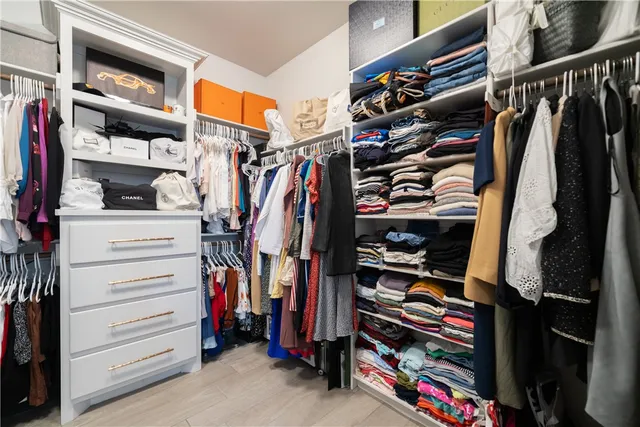 a view of walk in closet with clothes and shoes