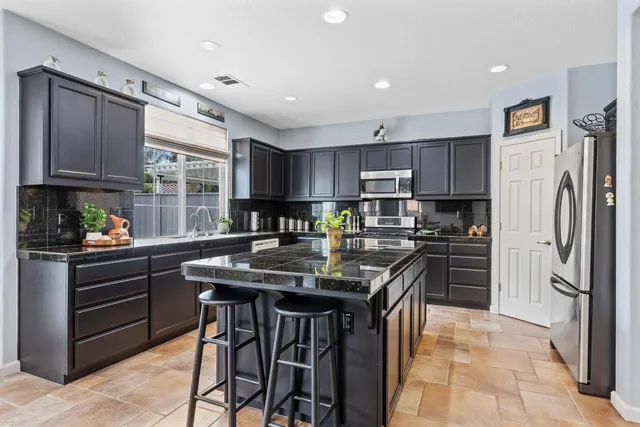 a kitchen with stainless steel appliances kitchen island granite countertop a refrigerator and a stove top oven
