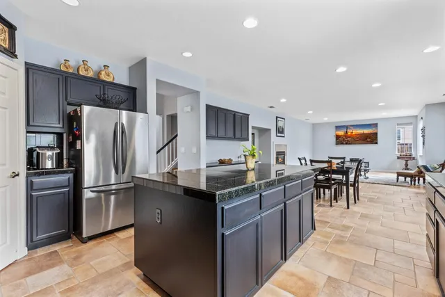 a kitchen with stainless steel appliances granite countertop a refrigerator oven a sink a dining table and chairs