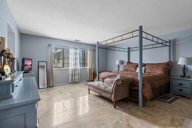 a bedroom with a bed and a flat tv screen on the dresser