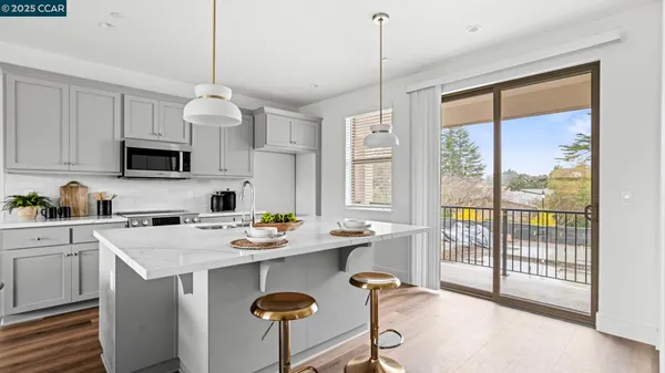 a kitchen with stainless steel appliances granite countertop a stove a sink a microwave a refrigerator a stove and white cabinets with wooden floor