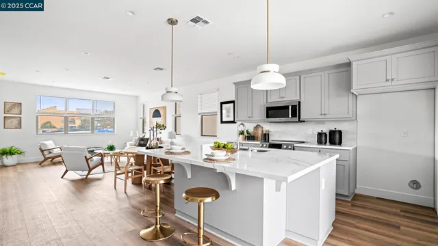 a open kitchen with stainless steel appliances granite countertop a stove top oven a refrigerator a sink dishwasher a dining table and chairs with wooden floor
