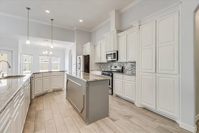 a kitchen with granite countertop white cabinets and stainless steel appliances