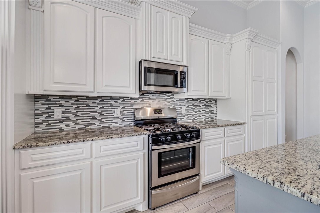 15501 Escapade Street Corpus Christi, TX 78418 - Photo 14 of 40 a kitchen with granite countertop white cabinets and stainless steel appliances