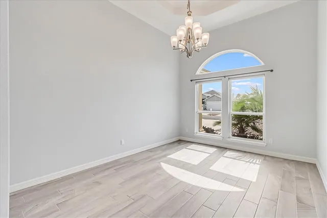 a view of a hallway with wooden floor and a chandelier