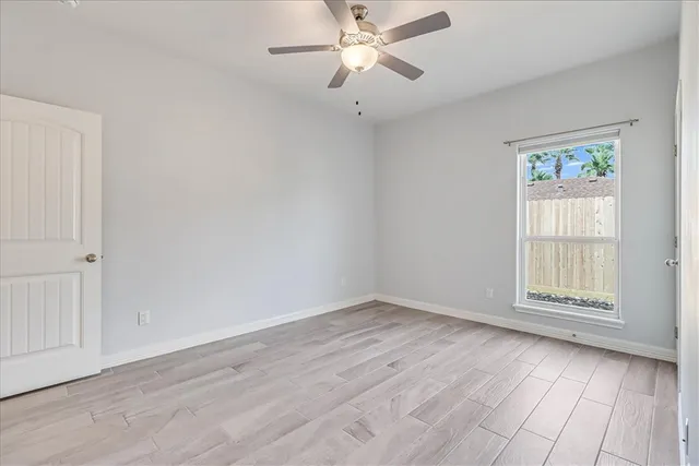 an empty room with wooden floor and ceiling fan