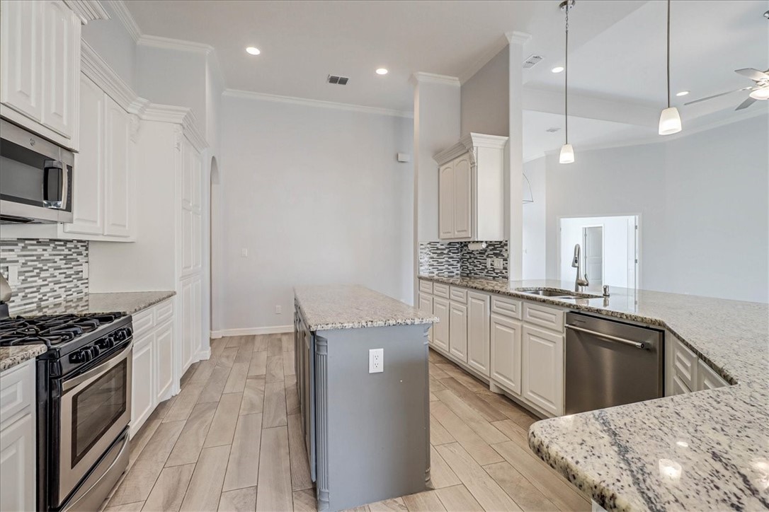 15501 Escapade Street Corpus Christi, TX 78418 - Photo 4 of 40 a kitchen with kitchen island a counter top space a sink stainless steel appliances and cabinets