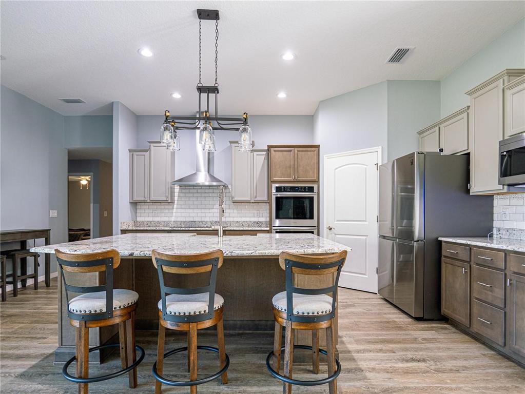10688 Southwest 129th Terrace Road Dunnellon, FL 34432 - Photo 10 of 35 a kitchen with granite countertop kitchen island stainless steel appliances a dining table chairs sink and cabinets