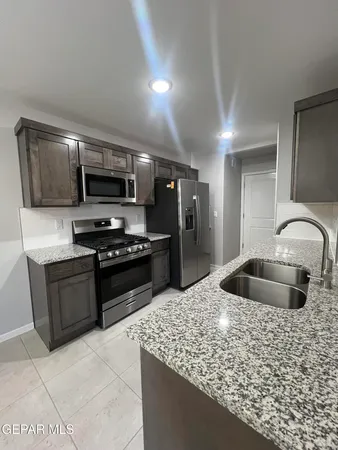 a kitchen with stainless steel appliances kitchen island granite countertop a sink and a stove top oven with wooden floor