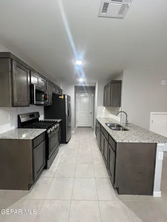 a large kitchen with stainless steel appliances granite countertop a stove top oven a sink dishwasher and a refrigerator