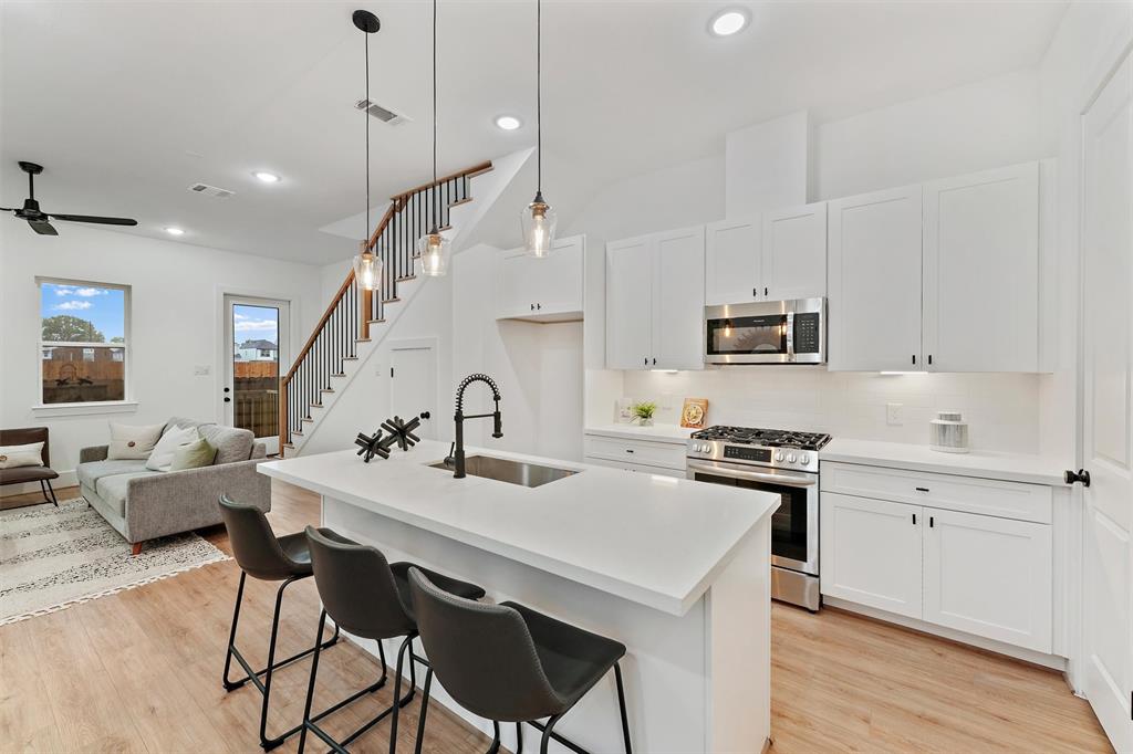 a kitchen with kitchen island granite countertop a sink a center island stainless steel appliances and cabinets