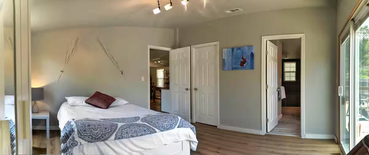 8807 High Valley Road Austin, TX 78737 - Photo 6 of 22 An inviting bedroom with light wood flooring, offering a peaceful retreat and direct outdoor access.