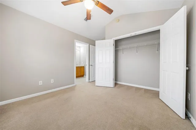 an empty room with closet and a ceiling fan