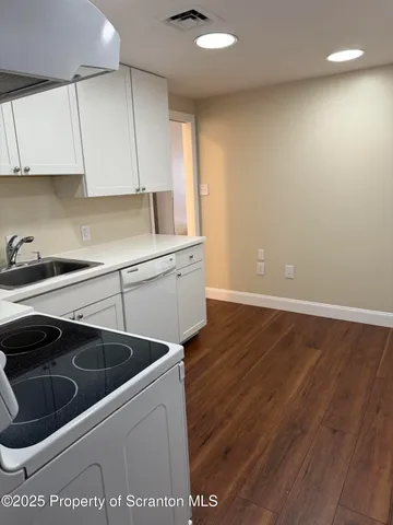 a kitchen that has a sink and a stove with wooden floor