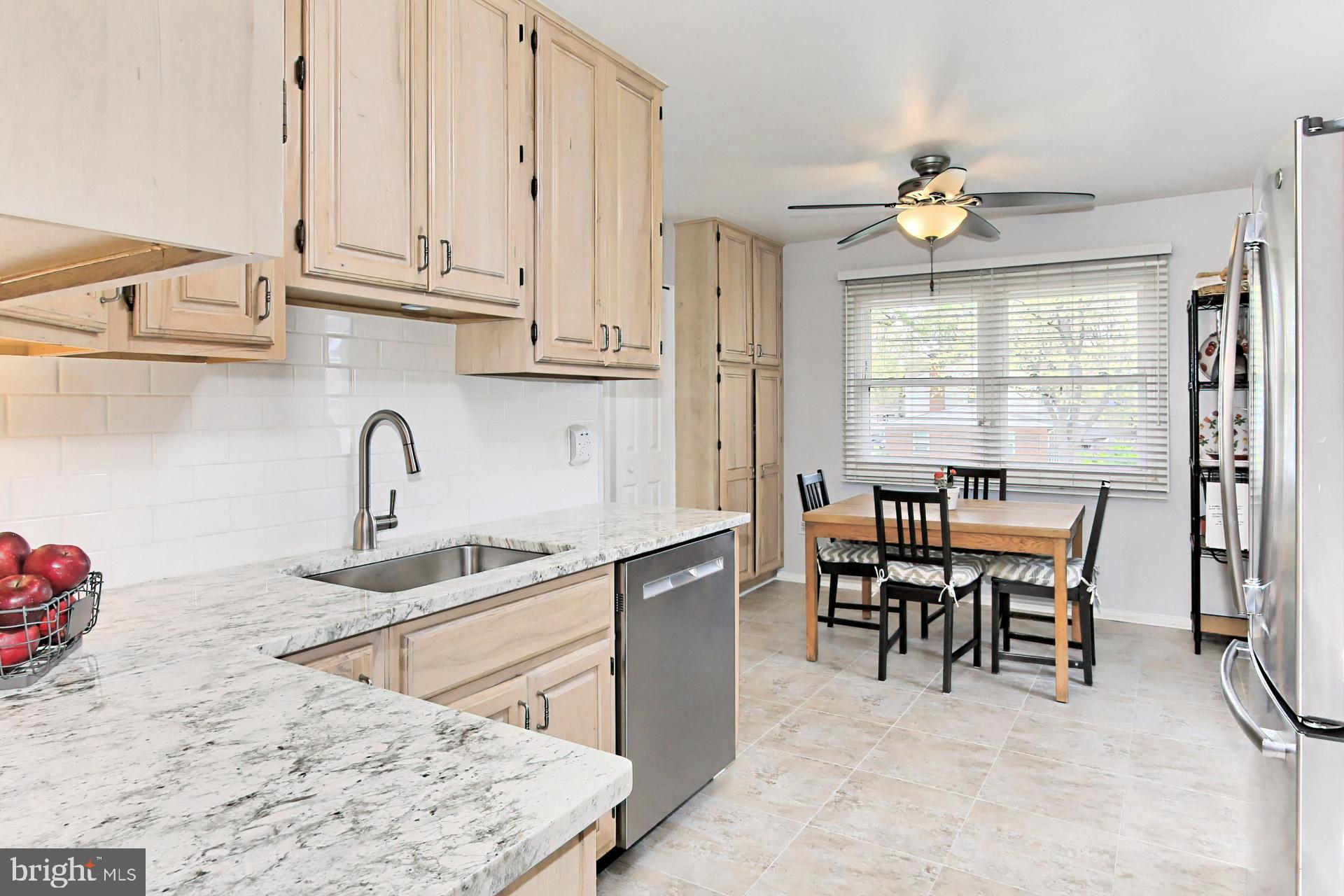 6011 Meriwether Lane Springfield, VA 22150 - Photo 13 of 53 a kitchen with stainless steel appliances granite countertop a stove top oven a sink a dining table and chairs with wooden floor